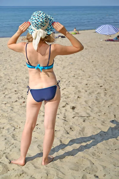 藁帽子の女性と別の水着は バルト海の砂浜の海岸に彼女の背中で立っています カリーニングラード地方 — ストック写真