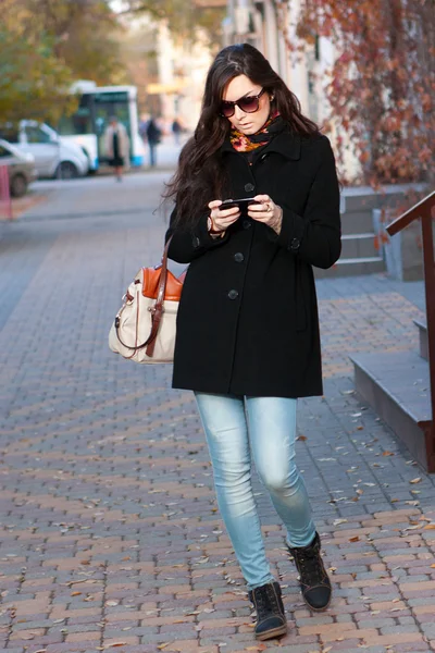 Frau mit Handy auf der Straße Stockbild