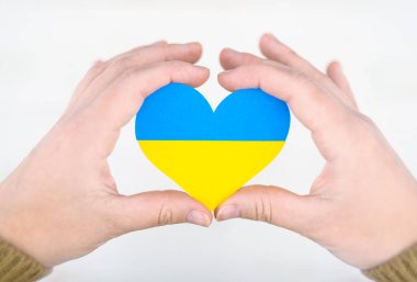 Ukrayna bayrağı renginde kalp ellerinde, yardım ve Ukrayna 'ya destek kavramı