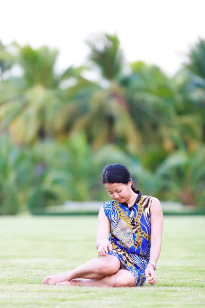 Азиатка сидит на земле в парке — стоковое фото
