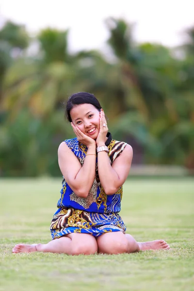 Aziatische vrouw zitten en glimlach in park — Stockfoto