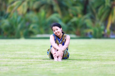Asyalı kadın sit ve gülümseme Park