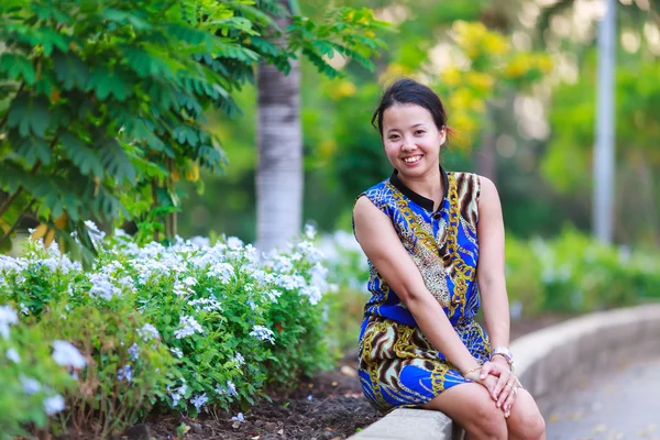 Aziatische vrouw zitten en glimlach in park — Stockfoto