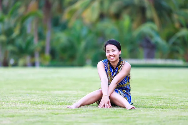 Азиатка сидит и улыбается в парке — стоковое фото