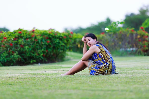 Aziatische vrouw zitten op grond in park — Stockfoto