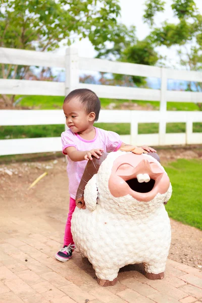 Asian baby girl ride sheep statue — Stock Photo, Image