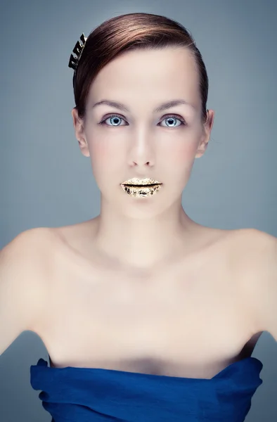 Azuurblauwe portret van een jonge vrouw met gouden lippen. — Stockfoto