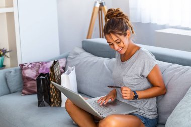 Güzel bir kadın kredi kartıyla online alışveriş yapıyor. Kredi kartı tutan ve laptop kullanan bir kadın. Çevrimiçi alışveriş kavramı