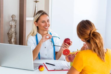Doktor diyetisyen, diyetisyen ve kadın hasta muayenede. Kadın beslenme uzmanı hastaya danışmanlık yapıyor. Diyet planı yapıyorum..
