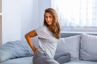 Evde sırt ağrısı çeken bir kadın. Bel Ağrısı. Kadın sırt ağrısı hisseder masaj yapar kaslar ağrır, üzgün kadın bel ağrısı çeker.