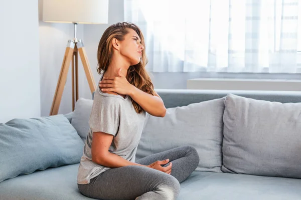 Pain in the shoulder. Upper arm pain, People with body-muscles problem, Healthcare And Medicine concept. Attractive woman sitting on the bed and holding painful shoulder with another hand.