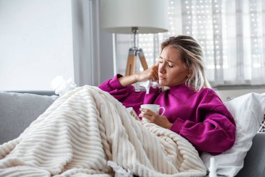 Hasta olduğu için evde. Sarışın kadın soğuk algınlığına yakalanmış. Öksür. Soğuk algınlığına ya da gribe yakalanmış güzel genç bir kadının yakın çekimi. Boğazında Ağrı Olan Sağlıksız Kızın Portresi.