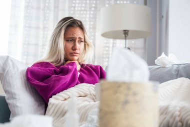 Hasta, çaresiz kadın grip olmuş. Rhinitis, soğuk, hastalık, alerji konsepti. Güzel hasta bir kadının burnu akıyor, burnu mendille sürtüyor. Hapşıran kadın. Esmer mendilin içinde hapşırıyor.