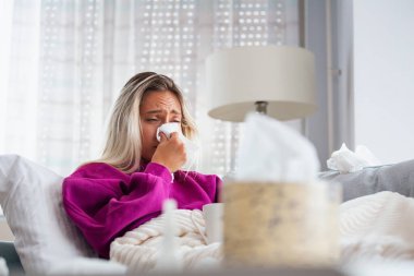 Hasta olduğu için evde. Sarışın kadın soğuk algınlığına yakalanmış. Öksür. Soğuk algınlığına ya da gribe yakalanmış güzel genç bir kadının yakın çekimi. Boğazında Ağrı Olan Sağlıksız Kızın Portresi.