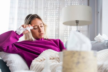 Hasta, çaresiz kadın grip olmuş. Rhinitis, soğuk, hastalık, alerji konsepti. Güzel hasta bir kadının burnu akıyor, burnu mendille sürtüyor. Hapşıran kadın. Esmer mendilin içinde hapşırıyor.
