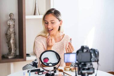 Ünlü blogger. Neşeli kadın vlogger kozmetik ürünler ise video kaydı ve onun güzellik blog için tavsiyeler vererek gösteriyor. Dijital kamera odaklama