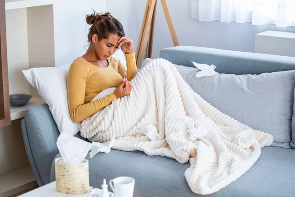 虚弱的女人穿着休闲装坐在沙发上吃药 生病的一天在家里 年轻女人感冒很常见 季节性病毒问题概念 — 图库照片