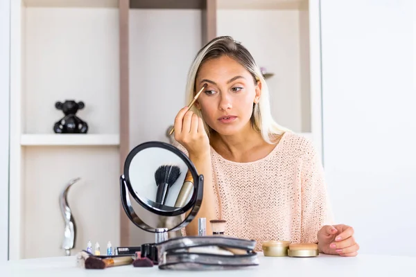 アイメイク女性アイシャドウパウダーを適用します 鏡の近くで化粧をして机に座っている若い美しい女性 — ストック写真