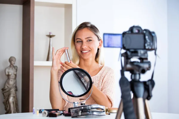 ビデオを録画しながら化粧品のパレットを持つ若い女性が話しています 女性メイキングビデオのために彼女のブログの化粧品 — ストック写真