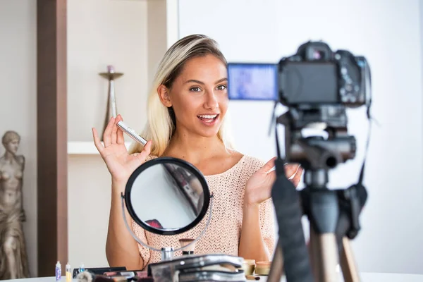 ビデオを録画しながら化粧品のパレットを持つ若い女性が話しています 女性メイキングビデオのために彼女のブログの化粧品 — ストック写真