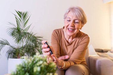 Glukometresi olan hamile bir kadında kan şekeri testi yapın. Parmakta şeker seviyesini ölçmeye hazır kırmızı bir kan damlası. Erkek parmağını kan damlası ve test şeridiyle kapat.