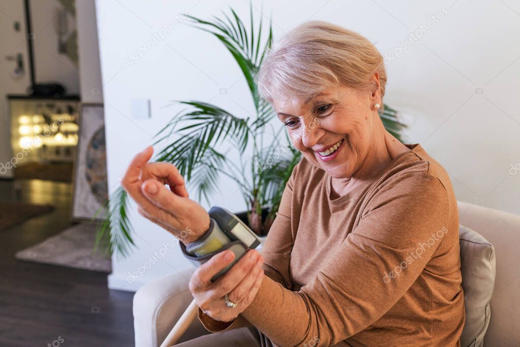 Mature Woman Checking Blood Pressure. Close up view of a blood pressure monito on hand. Digital tonometr on human hand. Portrait of Senior woman measuring her blood pressure