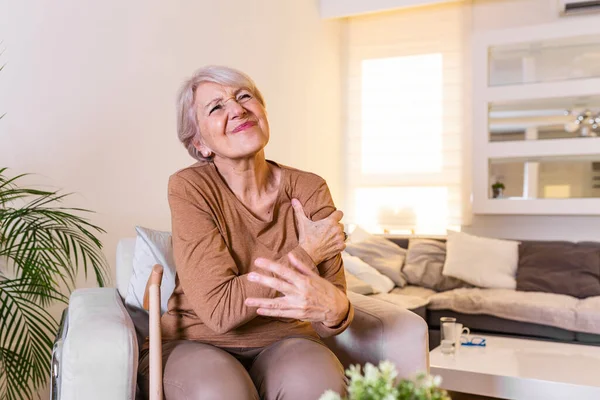 Elderly woman massaging the shoulder easing the aches. Joint pain concept. Senior old lady experiencing severe arthritis rheumatics pains, massaging, warming up arm. Close up, copy space, background