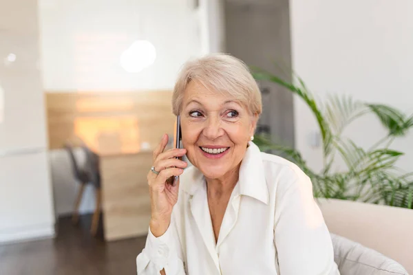 Ευτυχισμένη Ηλικιωμένη Γυναίκα Που Χρησιμοποιεί Κινητό Τηλέφωνο Στο Σπίτι Χαμογελώντας — Φωτογραφία Αρχείου