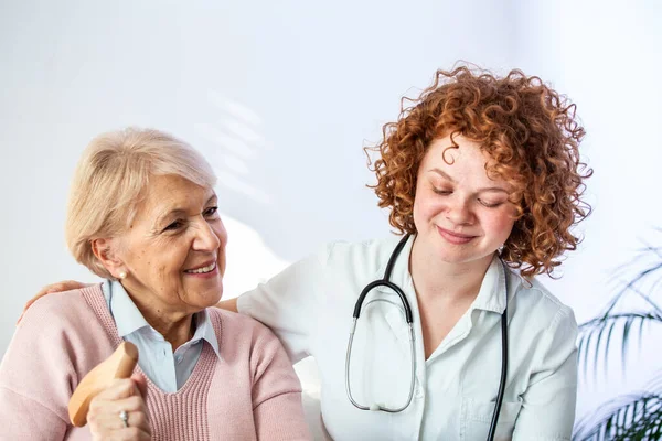 Mutlu hasta, birlikte zaman geçirirken bakıcıya yardım ediyor. Huzurevindeki yaşlı kadın ve hemşire. Huzurevinde yaşlanmış zarif bir kadın.