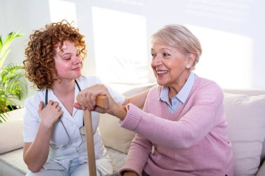 Close positive relationship between senior patient and caregiver. Happy senior woman talking to a friendly caregiver. Young pretty caregiver and older happy woman clipart