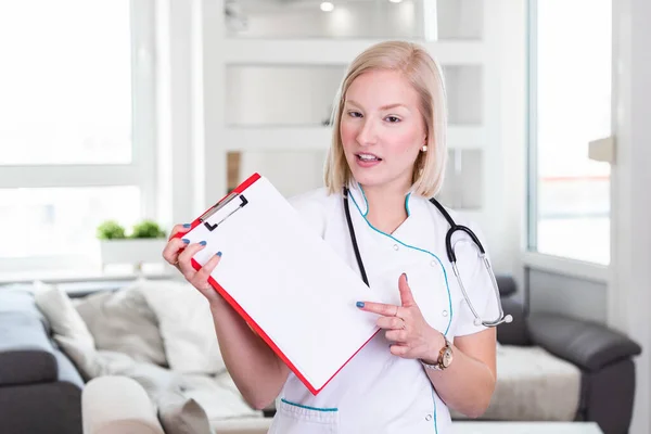 Happy doctor holding empty blank in hands. Female doctor showing a clipboard with blank paper. Close-up of a female doctor with lab coat and holding blank clipboard