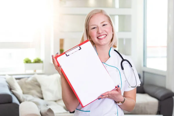 Happy doctor holding empty blank in hands. Female doctor showing a clipboard with blank paper. Close-up of a female doctor with lab coat and holding blank clipboard