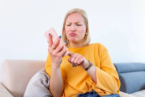 Frustrated woman having problem with not working smart phone sitting at home office desk, indignant confused woman annoyed with discharged or broken cell, received bad news in mobile message