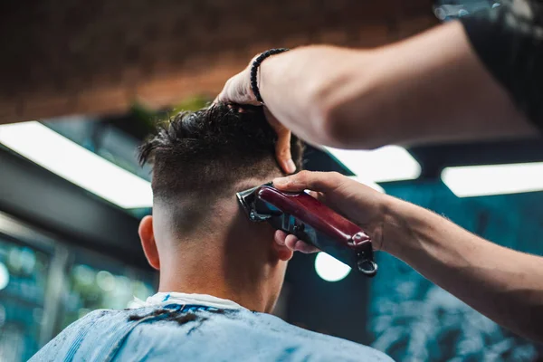 理髪店でトレンディなヘアカットを得る男のショットを閉じる 男性ヘアスタイリスト提供クライアント マシンと櫛を使用してのヘアカット — ストック写真