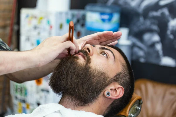 Beard styling and cut. Close up cropped photo of a styling of a beard. So trendy and stylish! Advertising and barber shop concept. Razor in hands of specialist barber