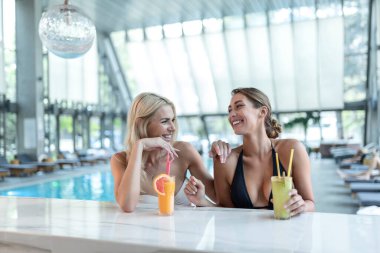 Kadın arkadaşlar içer, bilardo barında kokteyl içer, tropikal adanın yakınında lüks bir otel giyer, dinlenir.