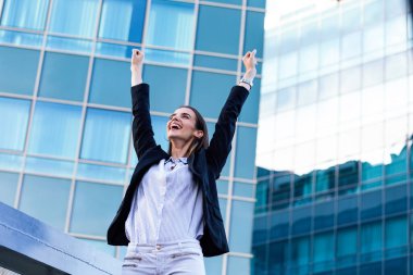 businesswoman in a business suit, exulted by happiness after finishing the deal, in the background skyscrapers. Concept of: business, technology, economy and work and success