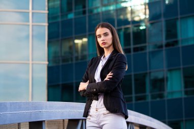 Çapraz kollu bir iş kadını. Ofiste büyük bir pencerenin yanında duran kendine güvenen modern iş kadını..