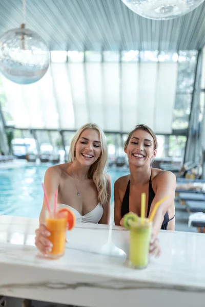 Women friends drink, cocktail mojito on pool bar, wear bikini luxury hotel near beach on tropical island relax