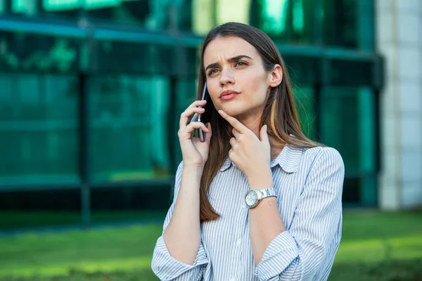 Business Woman thinking while talking on her mobile phone. business woman holding clipboard. Modern, hardworking woman holding clip board in hands, writing on documents