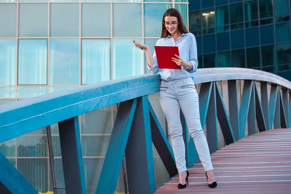 Executive business woman with clipboard against the urban background