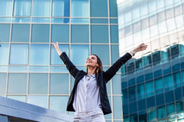 businesswoman in a business suit, exulted by happiness after finishing the deal, in the background skyscrapers. Concept of: business, technology, economy and work and success