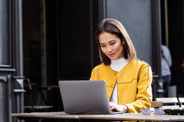 Modern kafe barında taşınabilir ağ-kitap laptopuyla oturan güzel Asyalı kadın, genç çekici Asyalı serbest yazar dizüstü bilgisayarla çalışırken yeni fikirler düşünüyor.