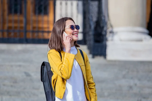 Portrait of a young, attractive and beautiful Asian woman smiling as she talks on her smartphone int he city. She is looking away as she talks animatedly and happily on her mobile device.