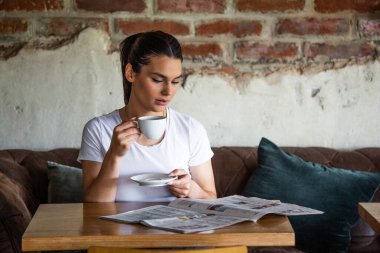 Kahvede dinlenirken güzel gülüşlü, gazete okuyan, boş zamanlarında kafede rahatlarken haber okuyan beyaz bir kadın.