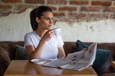Kahvede dinlenirken güzel gülüşlü, gazete okuyan, boş zamanlarında kafede rahatlarken haber okuyan beyaz bir kadın.