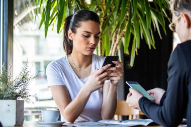 Teke tek görüşme. Kafedeki masada oturan iki genç iş kadını. Kız bilgisayar ekranında iş arkadaşı bilgilerini gösteriyor. Akıllı telefon kullanan, blog yazan bir kız. Takım çalışması, iş toplantısı. Serbest çalışanlar.