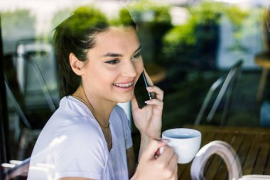 Genç, çekici bir kadın cep telefonuyla arıyor. Boş zamanlarında kafede tek başına oturuyor. Güzel gülüşlü çekici bir kadın kafede dinlenirken cep telefonuyla konuşuyor.