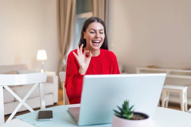 Heyecanlı genç bir kadın kameraya bakıyor, internette iş arkadaşlarıyla komik sohbetler yapıyor, webcam görüntüsü. Kulaklıklı genç bir kadının gülüşü, ev ofisinden eğlenişi..