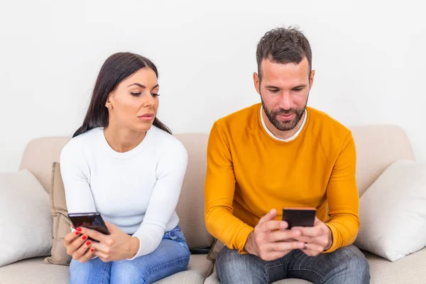 Jealous Young Woman Smartphone Looking Smiling Boyfriend Using Smartphone Home — Stockfoto